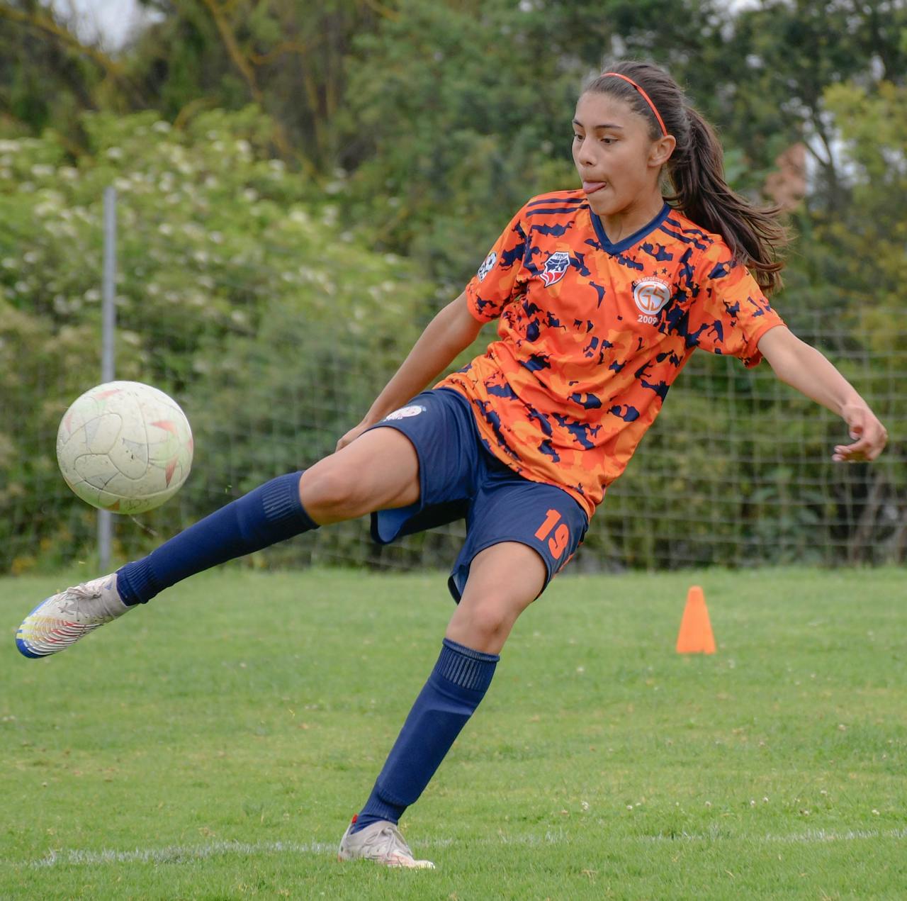 Young female soccer player in action on field, showcasing her skills and concentration.