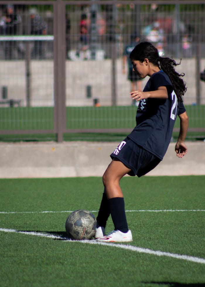 Young female soccer player controlling the ball on a sunny outdoor field.